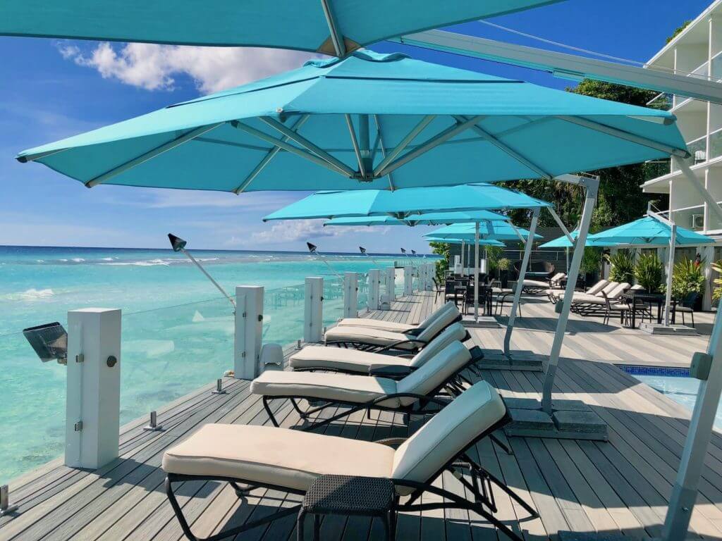 A row of pool loungers with blue umbrellas on the pool deck of the south gap hotel Barbados, St. Lawrence Gap