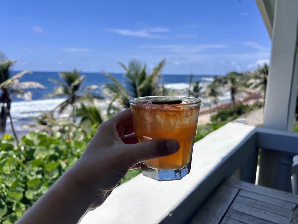 Nicola holding a rum punch with the east coast beaches in the background