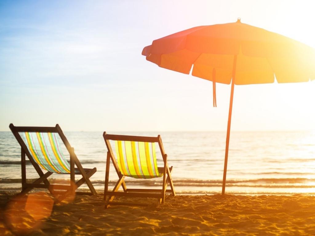 Two beach chairs and an umbrella on a beautiful beach at sunset