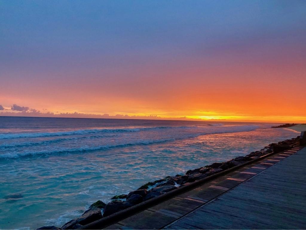 A red, orange, and pink sunset as seen from the south coast boardwalk, one of the best places to watch the sunset in Barbados