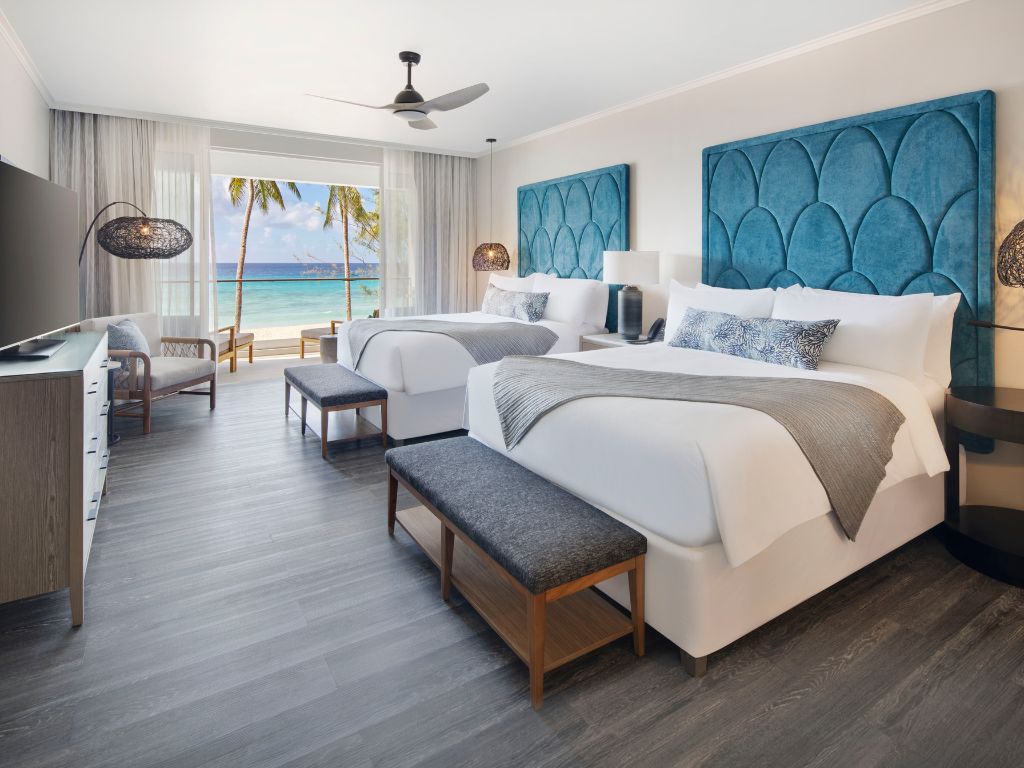 A guest room at O2 Beach Club and Spa with two large beds and a sea view