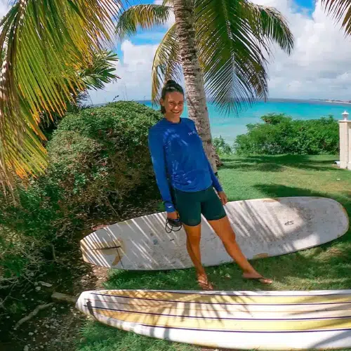Nicola standing beside two surf boards in Barbados